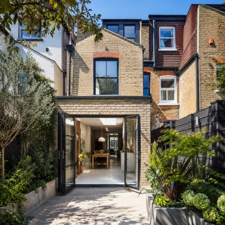Exterior rear view of a renovated Victorian terrace house with open bi-fold doors, site of a 130m² low-profile wet underfloor heating installation