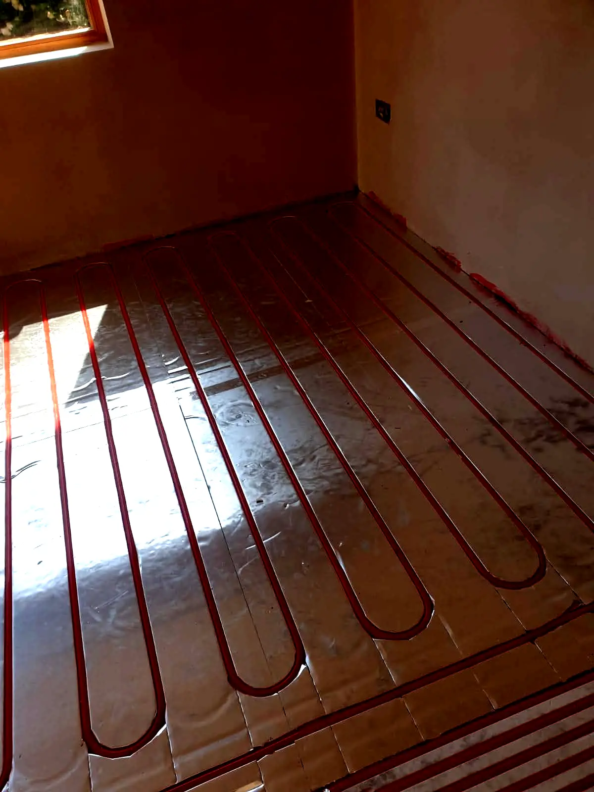 Narrow hallway floor fitted with red wet underfloor heating pipes on insulation, Cedar Close project