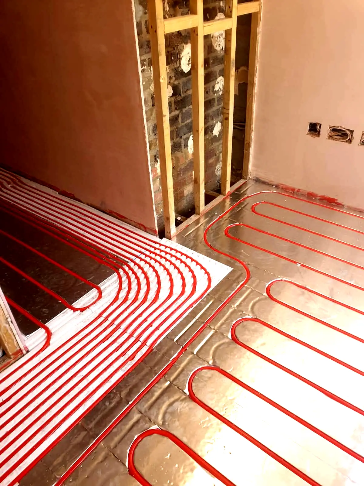 Underfloor heating pipe routes laid along timber frame internal wall during construction at Cedar Close