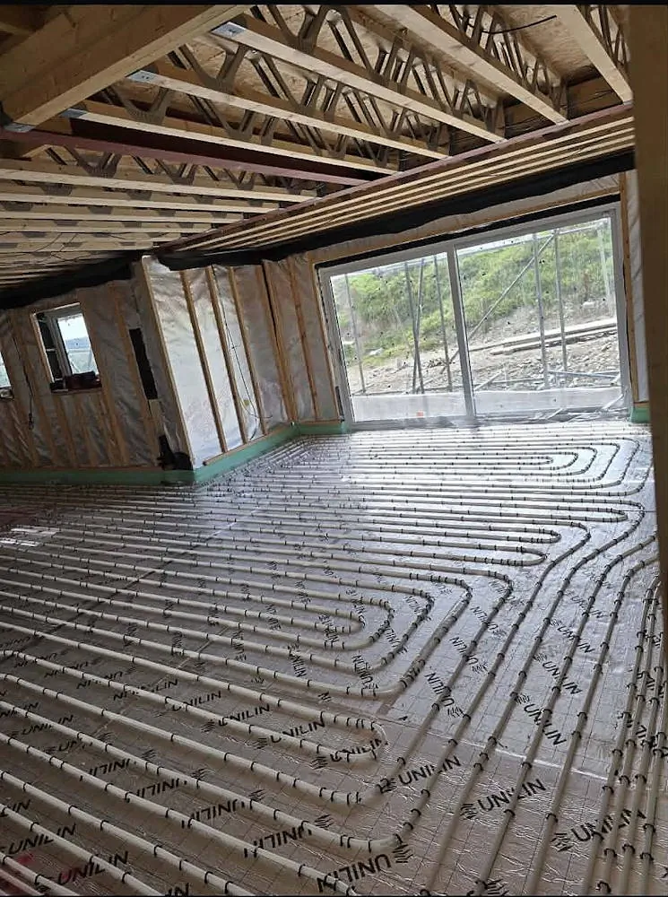 Spacious open-plan room with sliding patio doors showing wet underfloor heating pipes installed on silver insulation panels