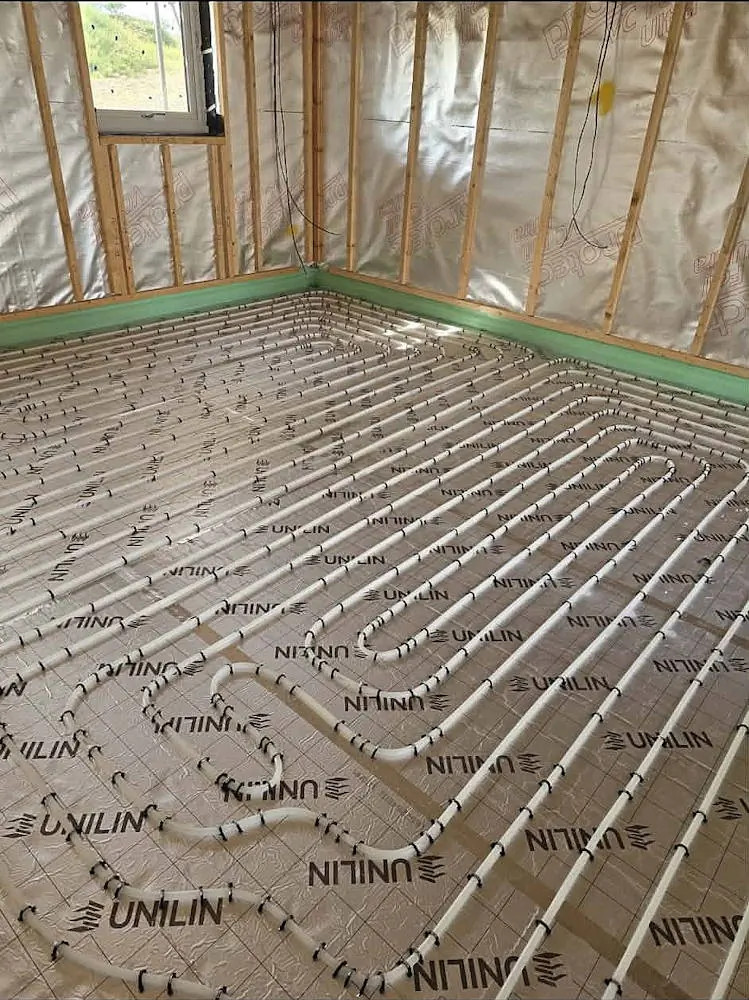 Wide view of wet underfloor heating installation across a large ground floor area with timber framing at Lakeside Villa
