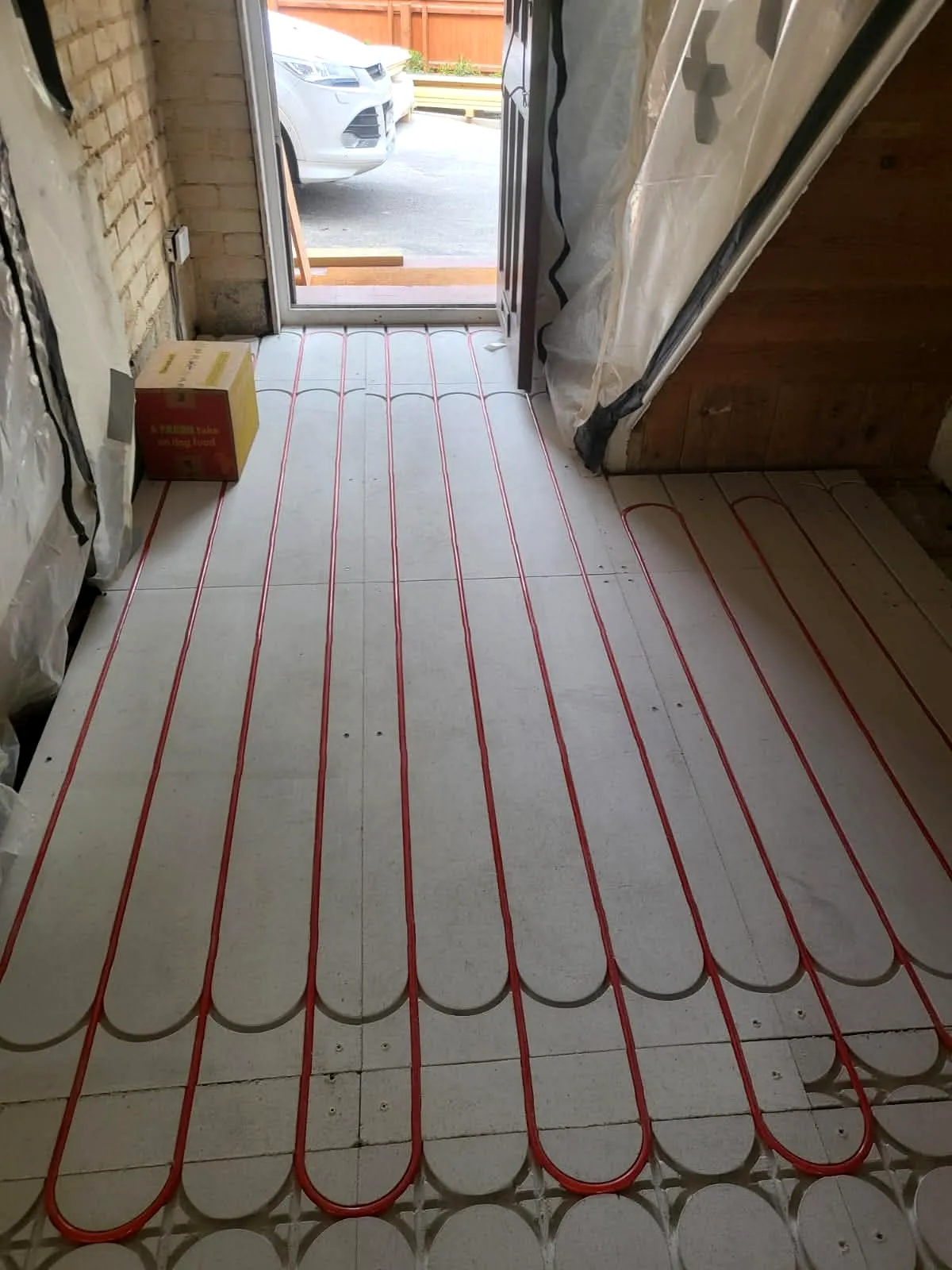 Underfloor heating installation in hallway leading towards front exit door, Sandbanks Road renovation project