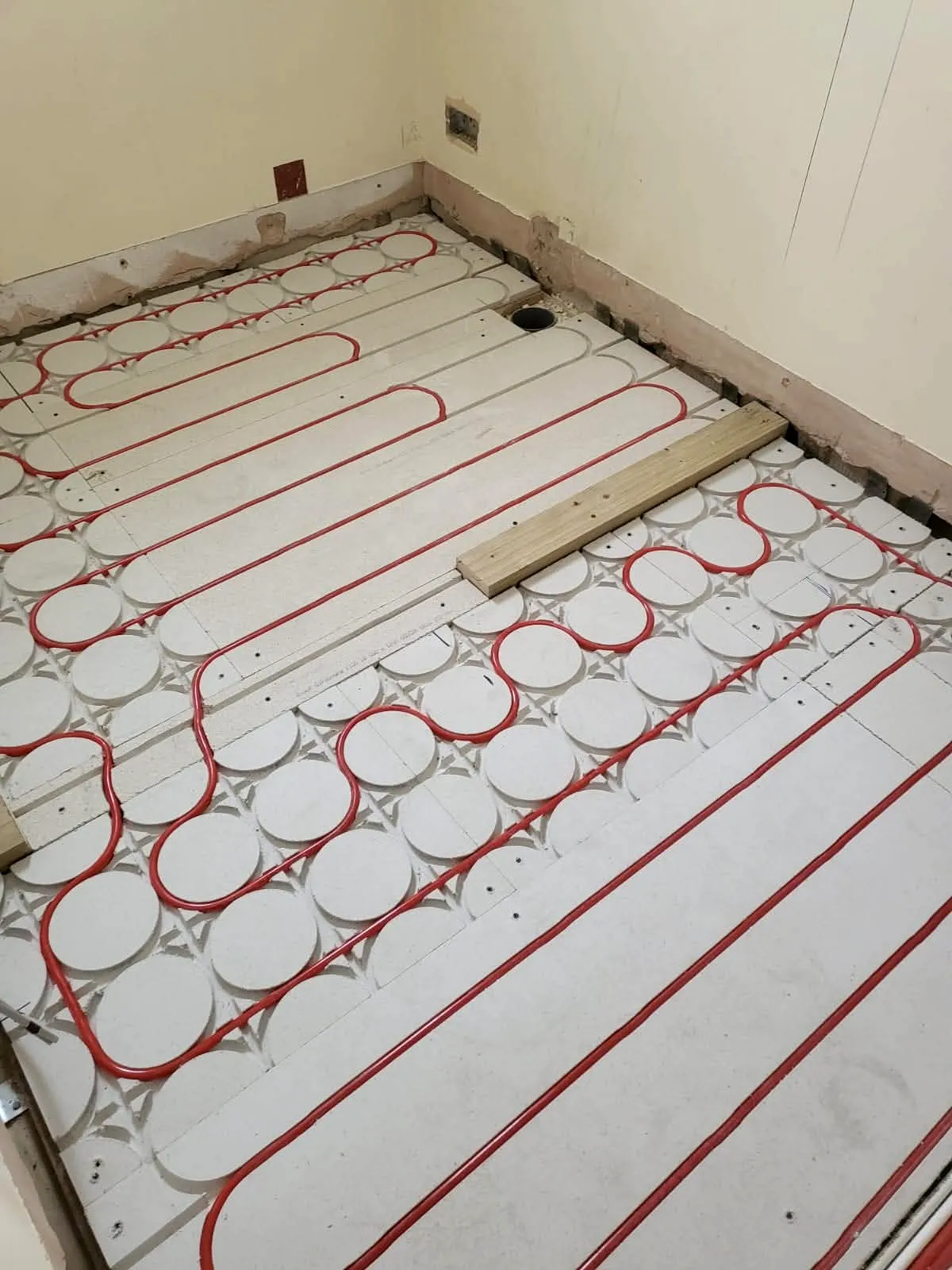 Parallel underfloor heating pipe runs laid on floor insulation prior to screed application, Sandbanks Road