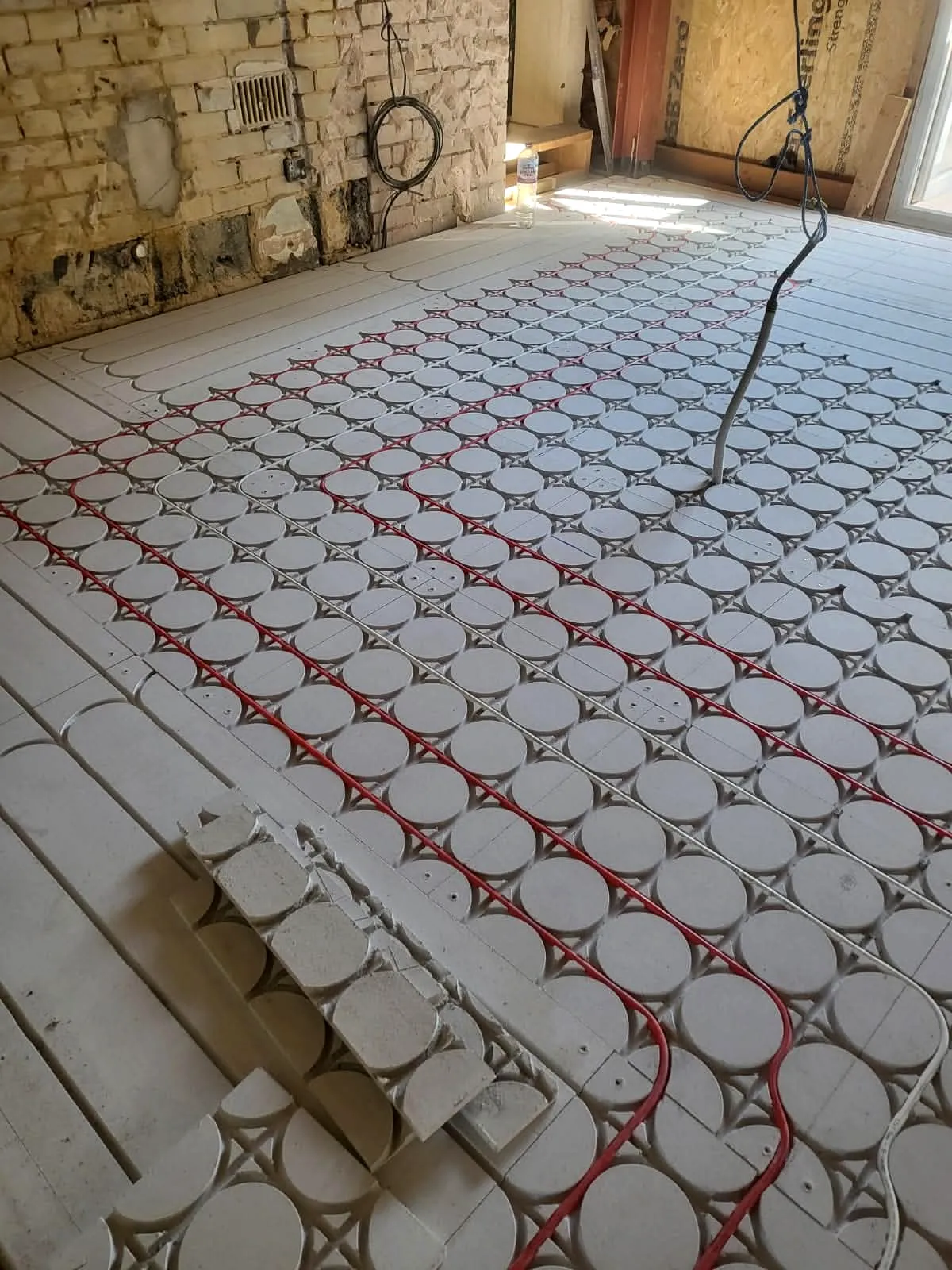 Overview of wet underfloor heating pipes installed in circular panels during Sandbanks Road property renovation
