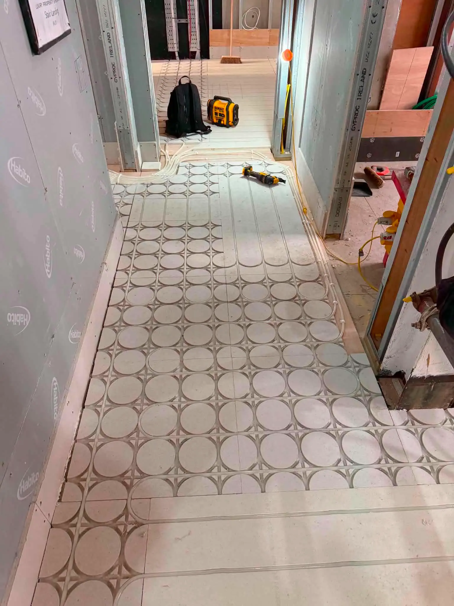 Narrow hallway fitted with white castellated underfloor heating insulation mats prior to pipe installation