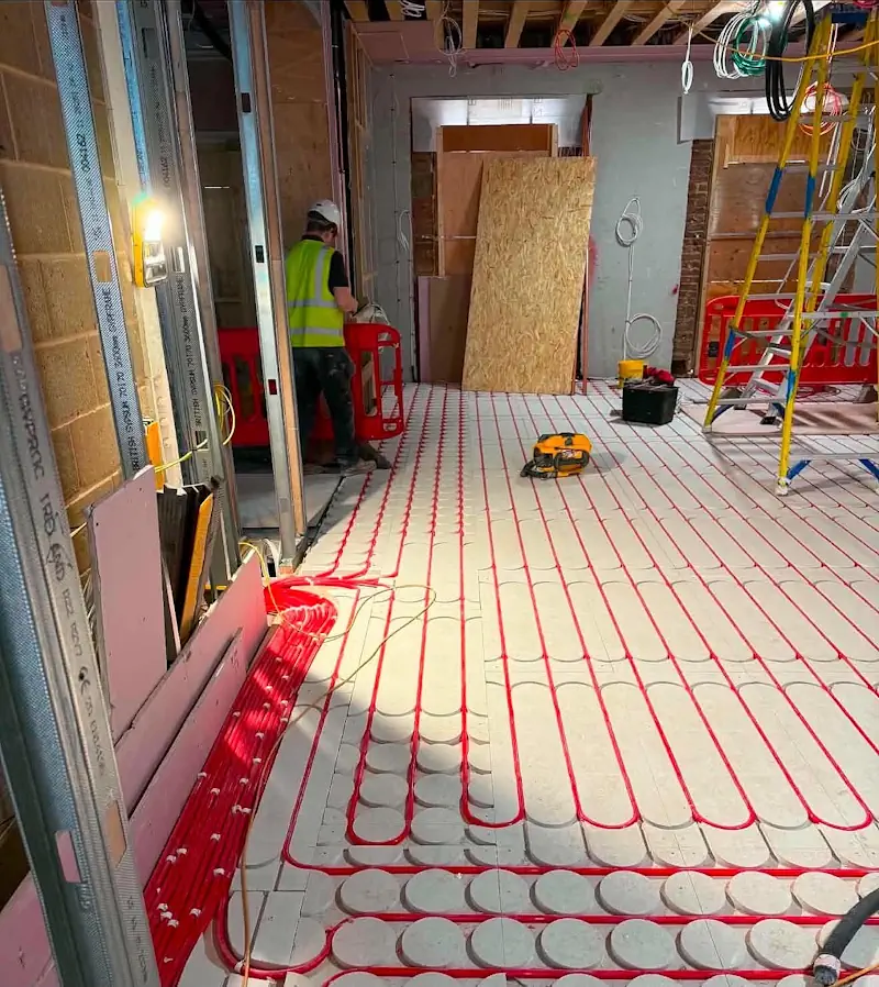 Interior construction view of underfloor heating pipe installation with temporary site lighting in a London penthouse