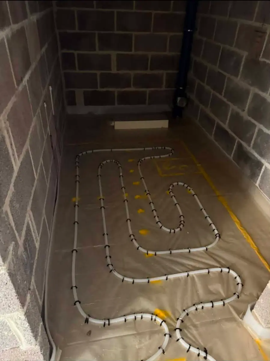 Underfloor heating pipework laid in grid formation across floor insulation before screed application at Oakwood Residence
