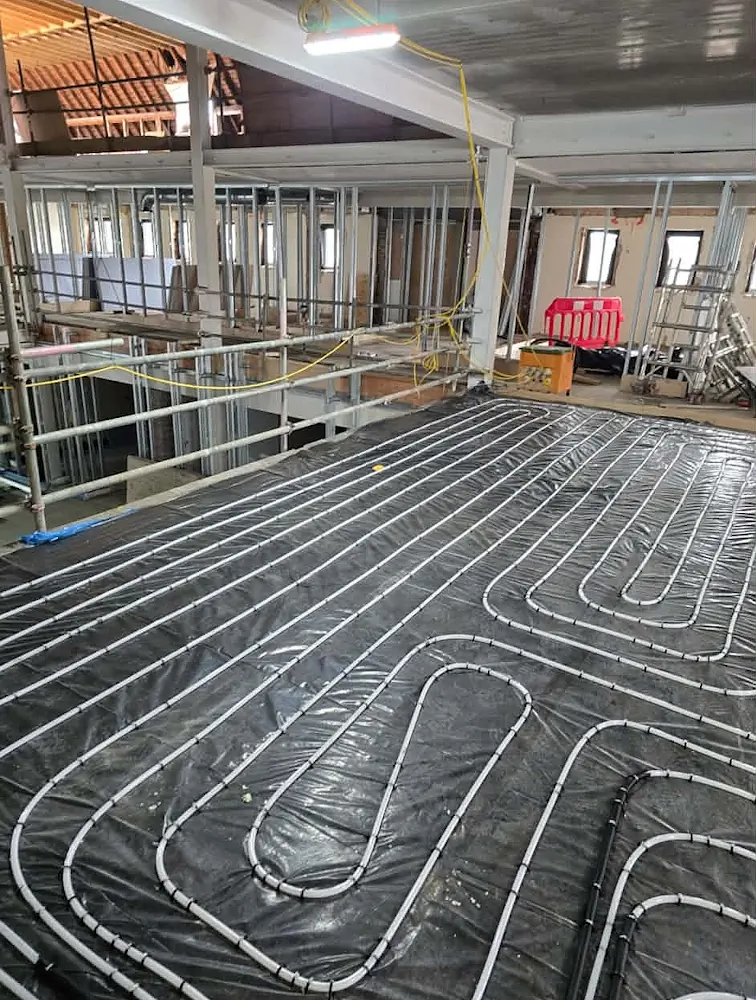 Underfloor heating pipework installed on black membrane near metal stud partitioning inside Westbrook Academy
