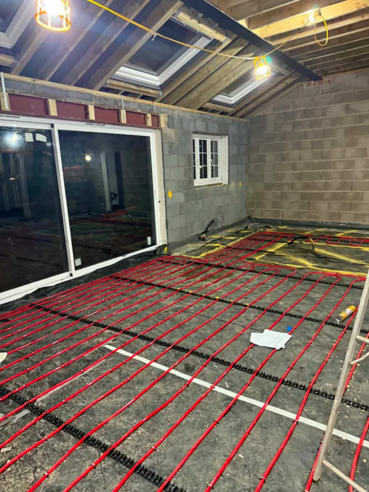 Construction interior view towards installed modern sliding glass doors with exposed underfloor heating pipes on the floor, Willow Grove
