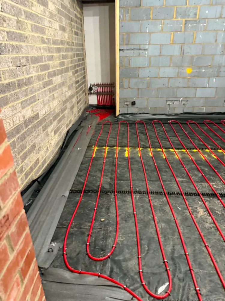 Comprehensive view of expansive floor area covered with red underfloor heating pipes in spiral pattern, Willow Grove project