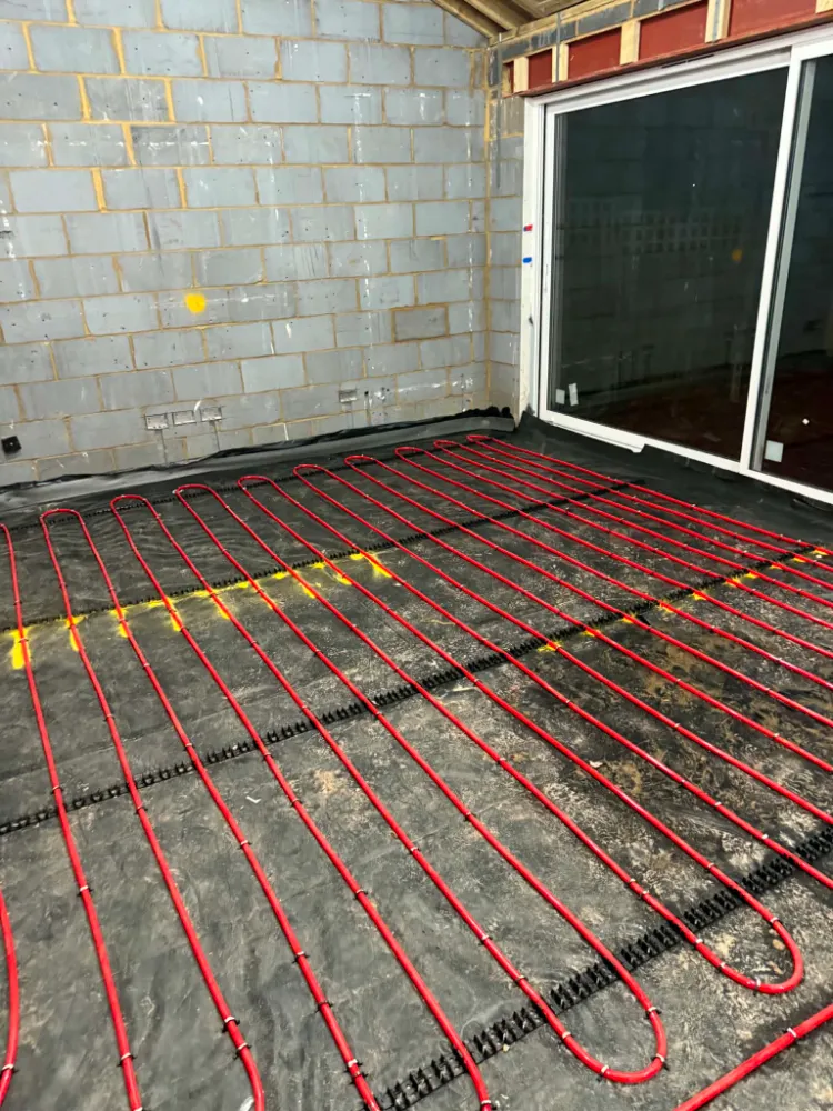 Interior construction room showing the grid network of red underfloor heating pipes at Willow Grove