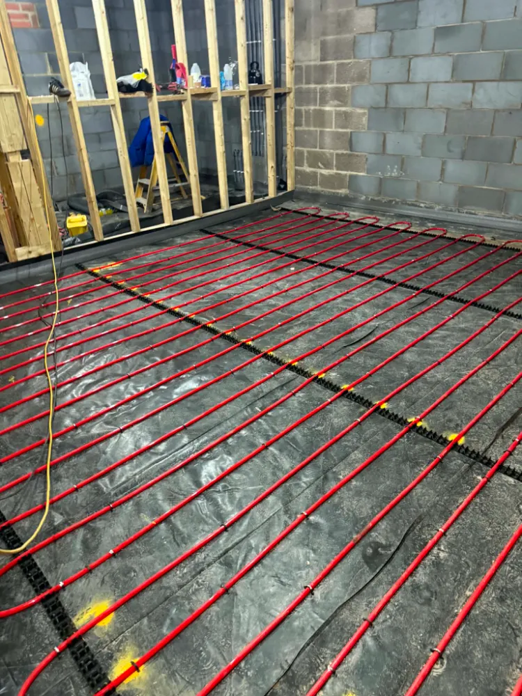 Close-up view of red underfloor heating pipes near wooden studwork framing at Willow Grove site